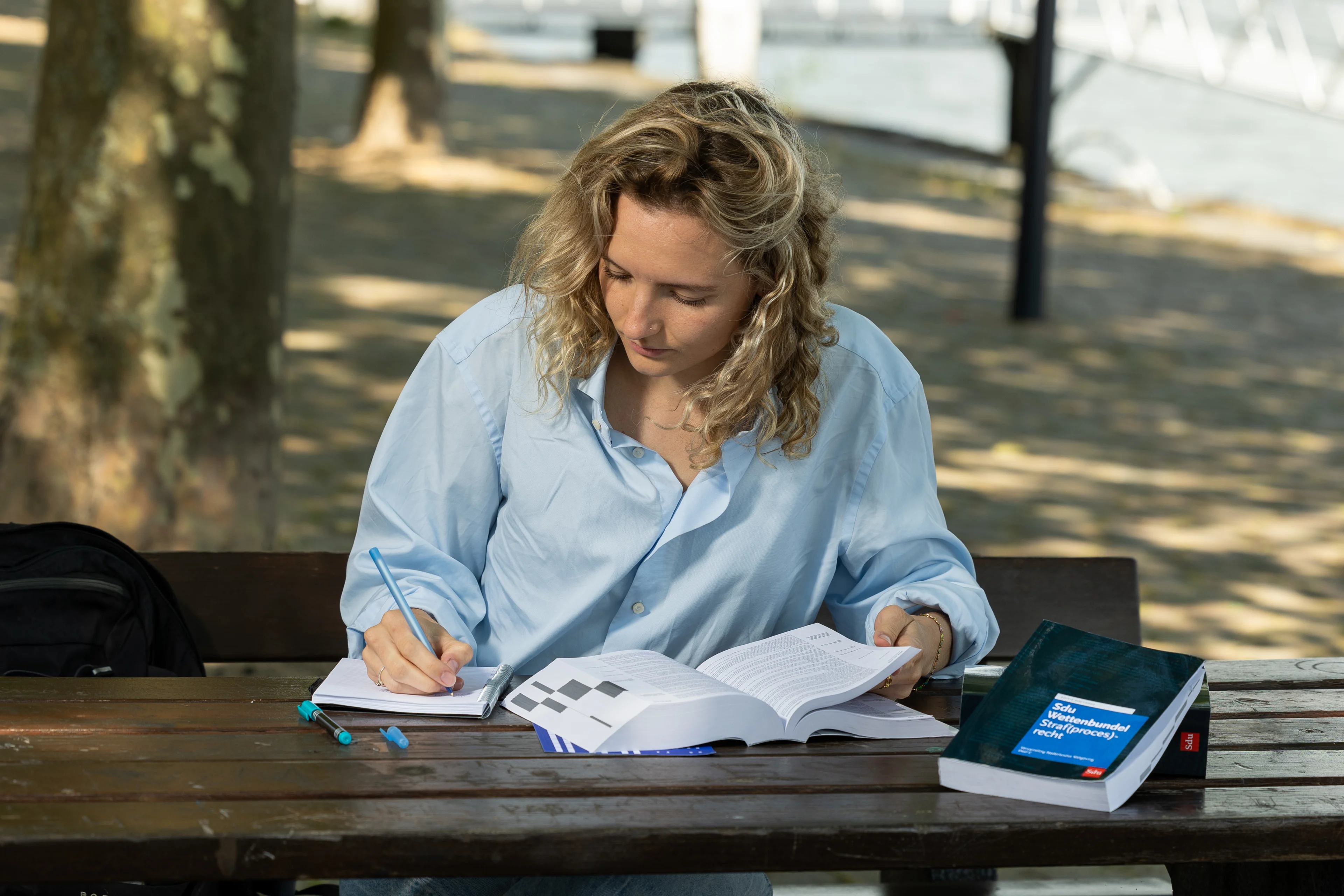 Vrouw met blond haar studeert buiten met de Sdu Wettenbundel