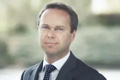 Man met bruin haar en een bril in pak