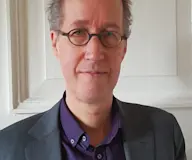 Man in pak met grijs haar en bril