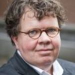 Foto van een man genaamd Wouter Burgerhart hij heeft een net pak aan en draagt een bruine bril met kort lichtgekruld bruin haar.