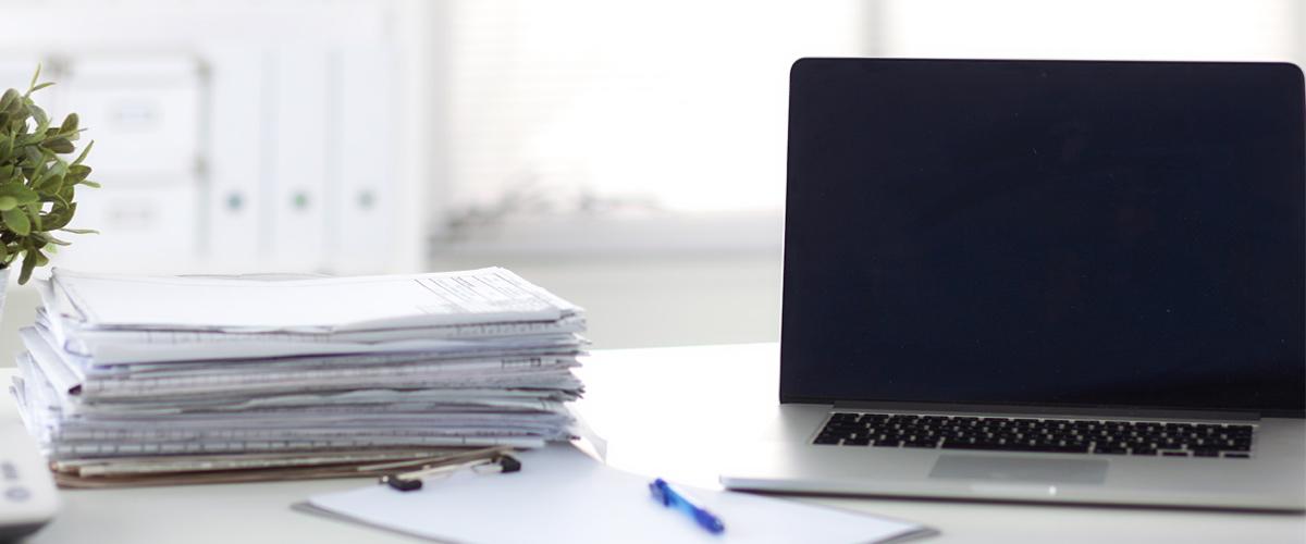 Laptop met stapel papier